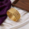 Gold bangles with red stones on a white fabric background