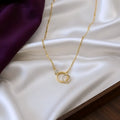Gold necklace with a circular pendant on a white fabric background