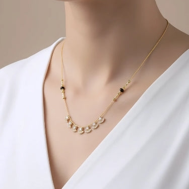 Gold necklace with black beads on a white background