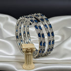 Shinayra by Nakhrali Creation set of 4 rhodium-plated bangles with alternating blue baguette and clear round CZ stones.