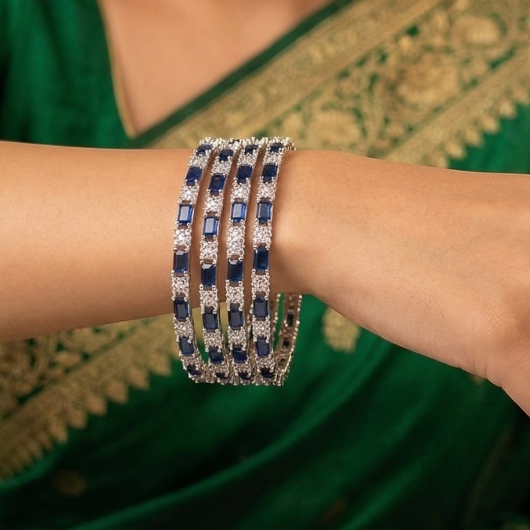 Shinayra by Nakhrali Creation set of 4 slim rhodium bangles with alternating blue baguette and white round CZ stones.