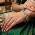 Shinayra by Nakhrali Creation set of 4 silver-toned bangles with oval multicolour CZ stones in green, blue, pink, and aqua.