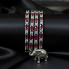 Shinayra by Nakhrali Creation set of 4 ruby red baguette and white round CZ tennis bangles with rhodium silver finish.